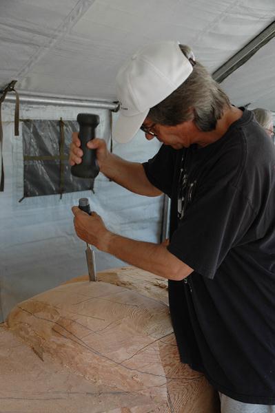 Tony Hunt Jr. using a stone hammer and chisel.
