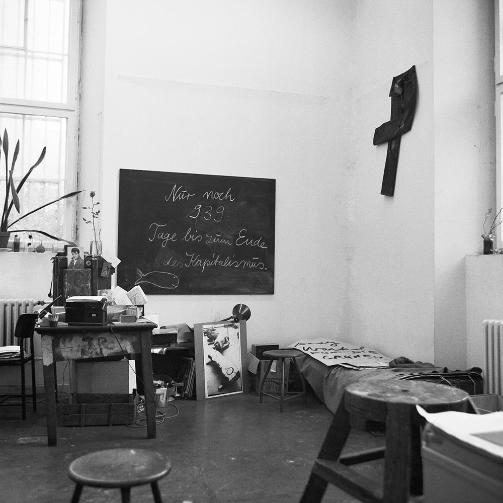 Robert Duchesnay <em>Large blackboard with “The end of capitalism in 939 days” statement and small sleeping cot in the corner with performance jeans above. The jeans were used during the “Good morning Mr. Orwell” performance in 1984 with videographer Nam June Paik</em> 1984 