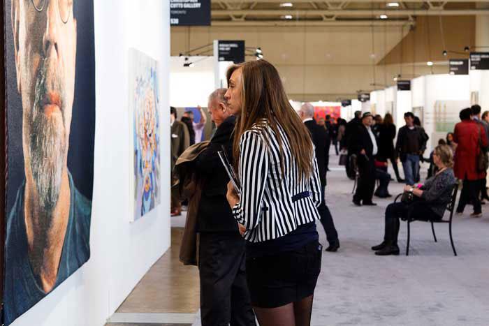 A visitor admiring <em>Self-Portrait</em> by Chuck Close at Galerie de Bellefeuille’s booth at Art Toronto 2011 / photo courtesy of Art Toronto and Arash Moallemi